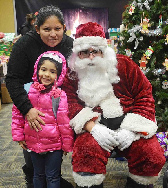  Port Chester's Emily Diaz, 5, and Luc Cayao pose with Santa Claus before the girl got a present. The many holiday gifts that were handed out on Friday, Dec. 18, were collected through a holiday toy drive hosted by the Open Door Foundation for families that utilize Open Door Family Medical Centers' facility in Port Chester. 