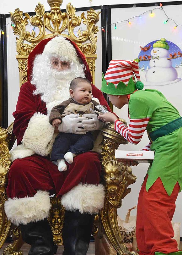  Ten-year-old Nicholas Santiago Massa of Port Chester offers a candy cane to baby Evelyn, held carefully by Santa, played by Port Chester's Nick Mecca. Hundreds of people, most of them young families, passed through Don Bosco Center on Saturday morning, Dec. 19 for the annual Breakfast with Santa event. 