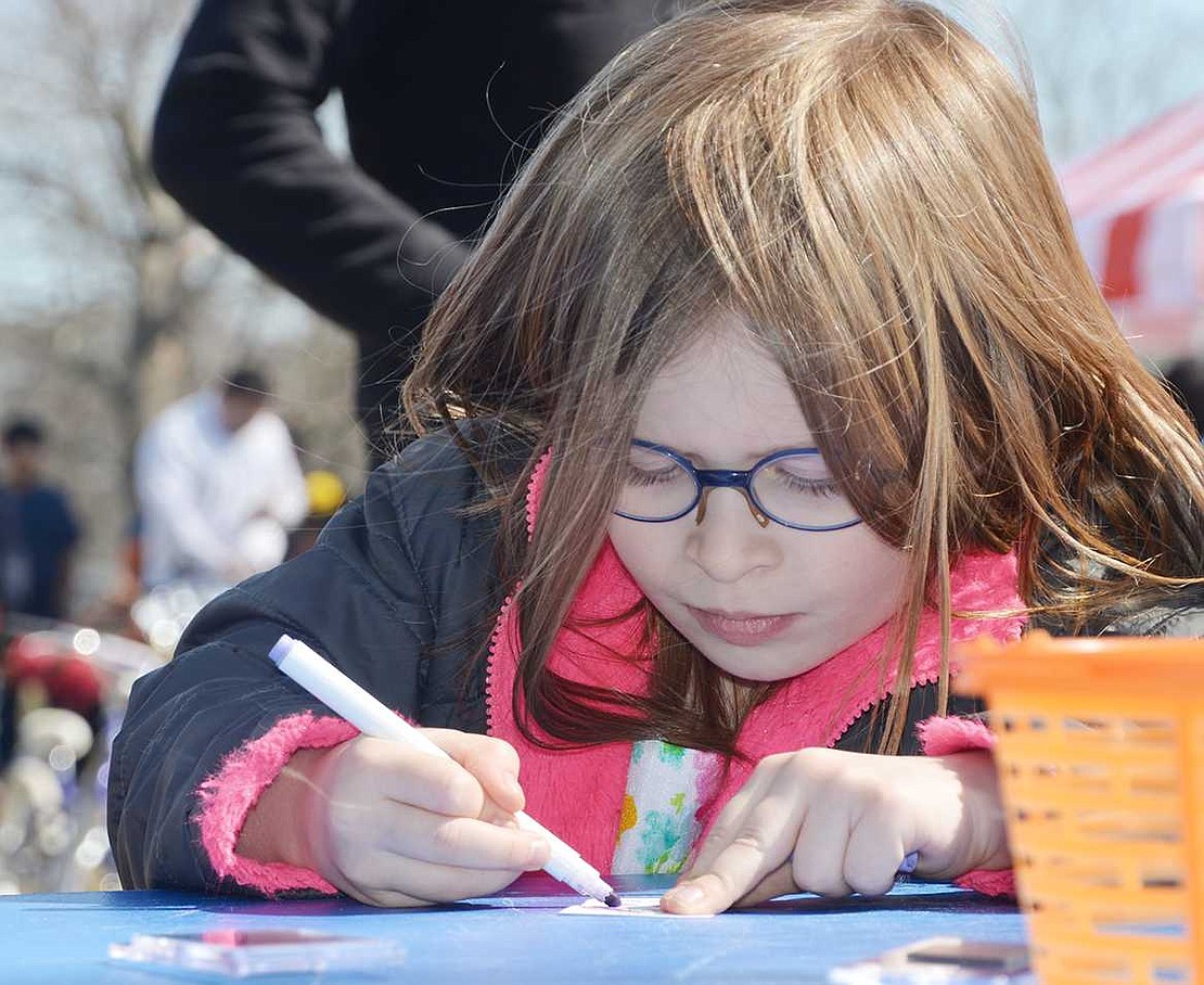 <p class="Picture">Port Chester 5-year-old Emily Kronforst carefully colors a piece of paper that will end up as part of a one-of-a-kind magnet.&nbsp;</p>