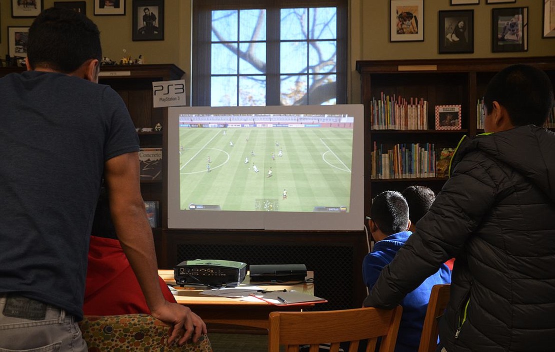  Teenagers avidly play a soccer game on the PlayStation 3. 