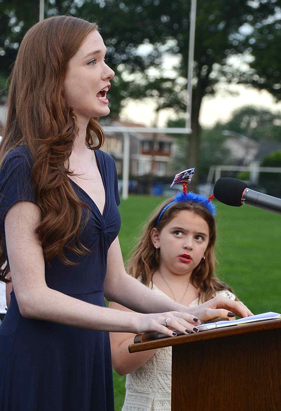 Robin Clifford sings the National Anthem as Madilyn Klein of Rye Brook looks on in awe.