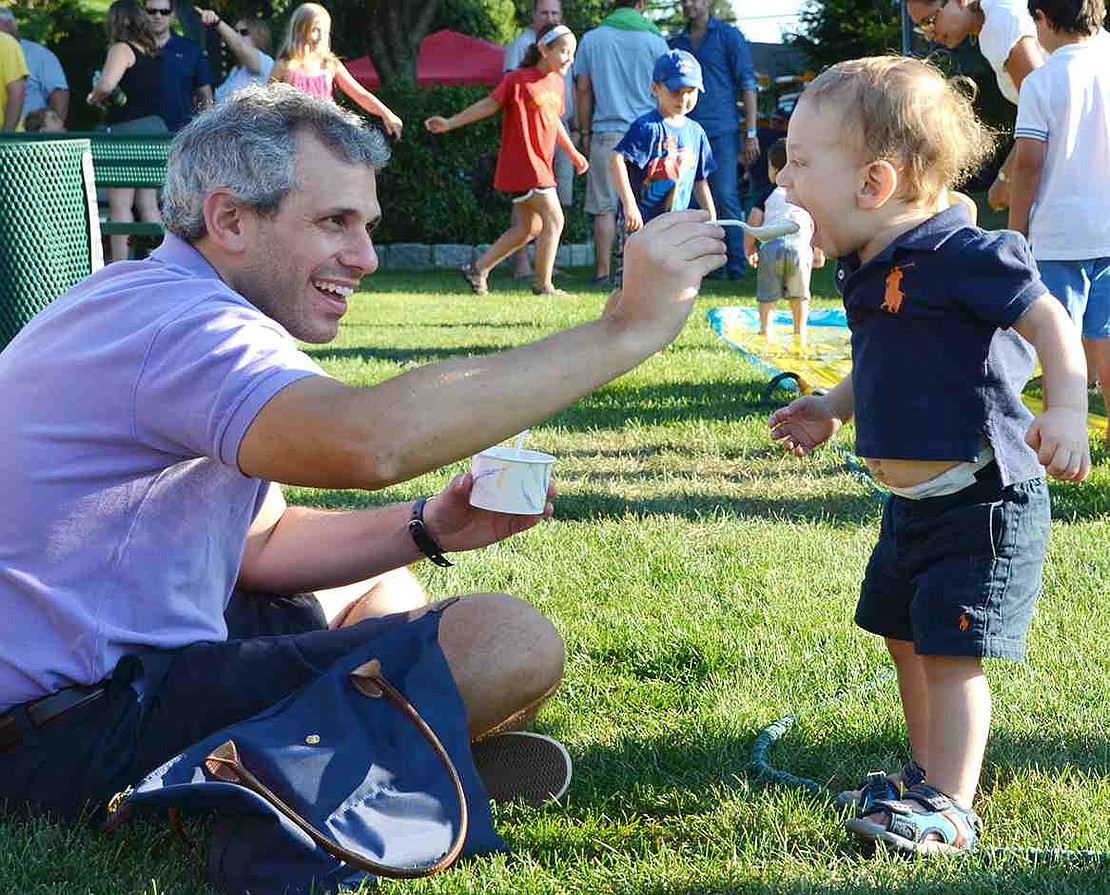 Mouth wide open, Alan takes a big bite of ice cream held out by his father, Fito Waisburg of Talcott Road. 