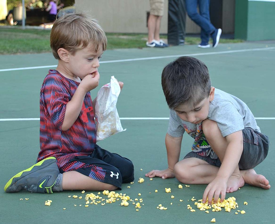 Three-year-olds Henry Zelman (left) of Bonwit Road and Matthew Paterno of Berkley Drive enjoying playing with their food-creating piles of popcorn on the basketball court-before eating it. 