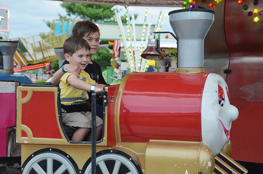 Rye Brook brothers Noah, 3, and Connor Kilgallen, 8, sit on a ride with cars shaped like little trains. 