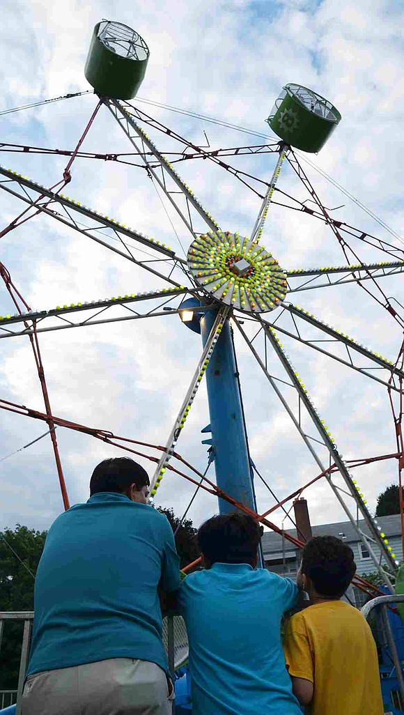 Carnival attendees stare up at one of the many rides set up behind Corpus Christi Church. 