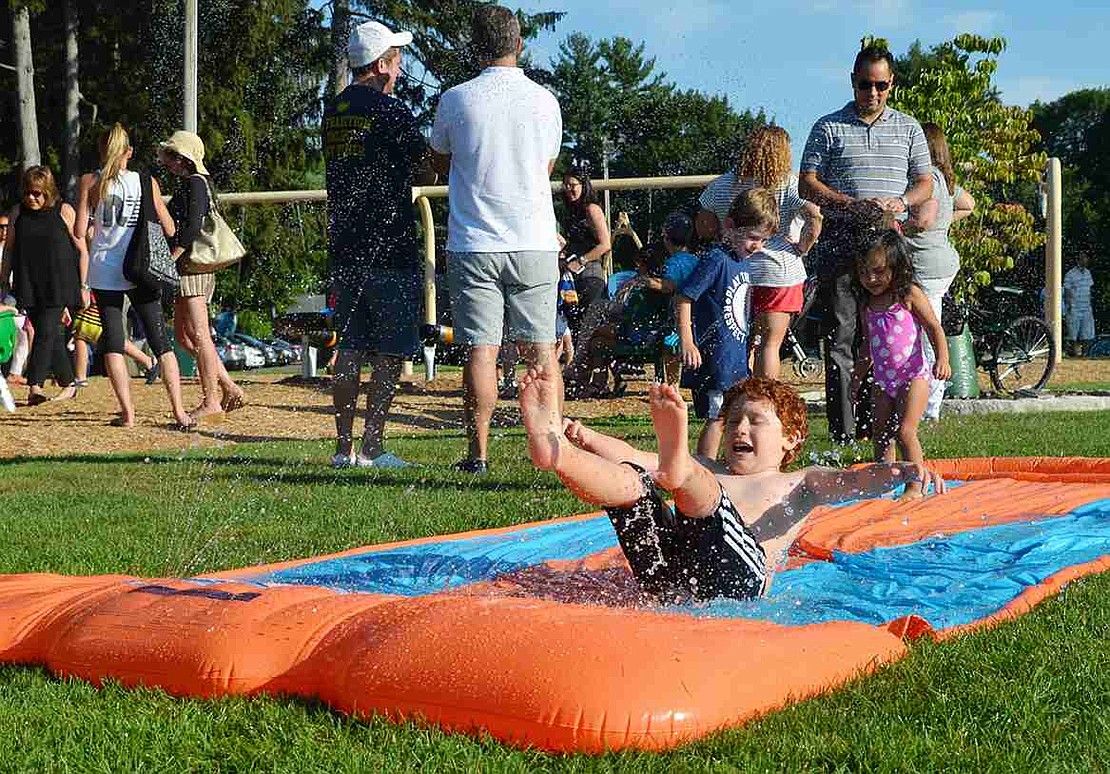Seven-year-old Pablo Zeitune of Old Oak Road skids feet first on one of the Slip 'n Slides set up in the park.