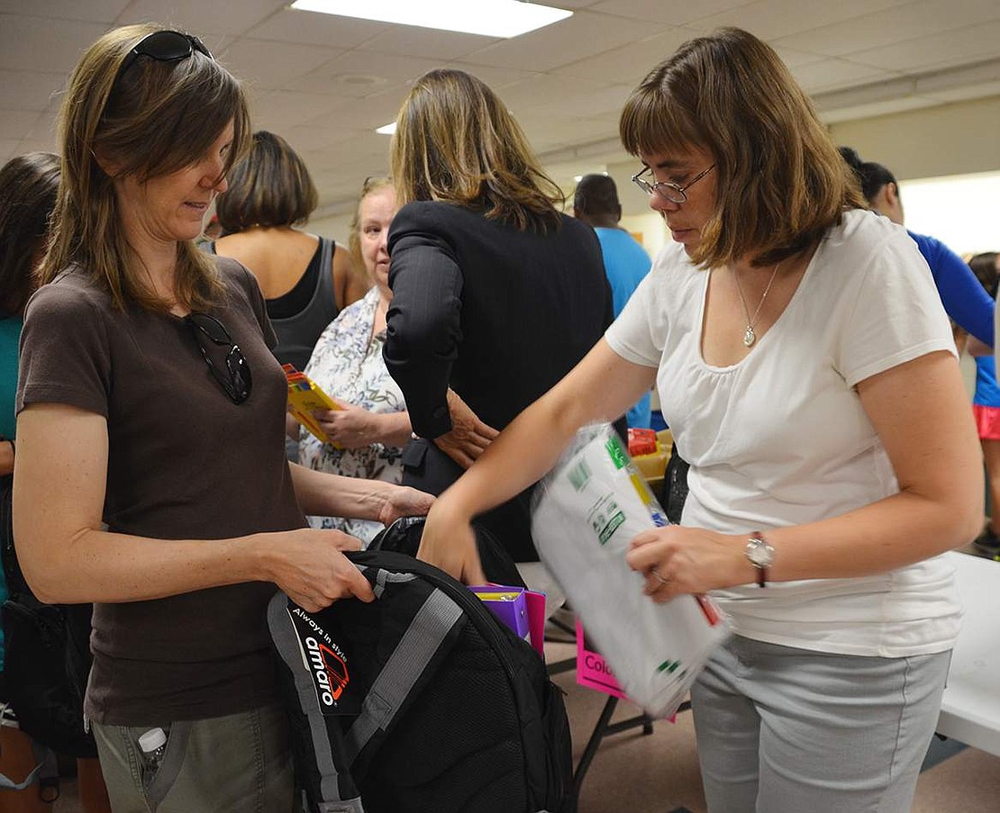  Laura Pugliese (right) of Wilton Road stuffs binder dividers into one of the backpacks for high school students.  