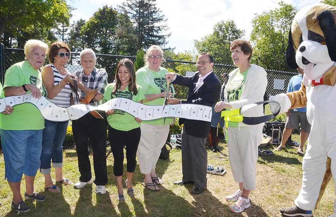 Members of the Port Chester Dog Park Group; Jerry Terranova, the chairman of the Port Chester Park Commission; and Port Chester Mayor Dennis Pilla cut a paper leash-rather than the traditional ribbon-to signify the official opening of the dog park. 