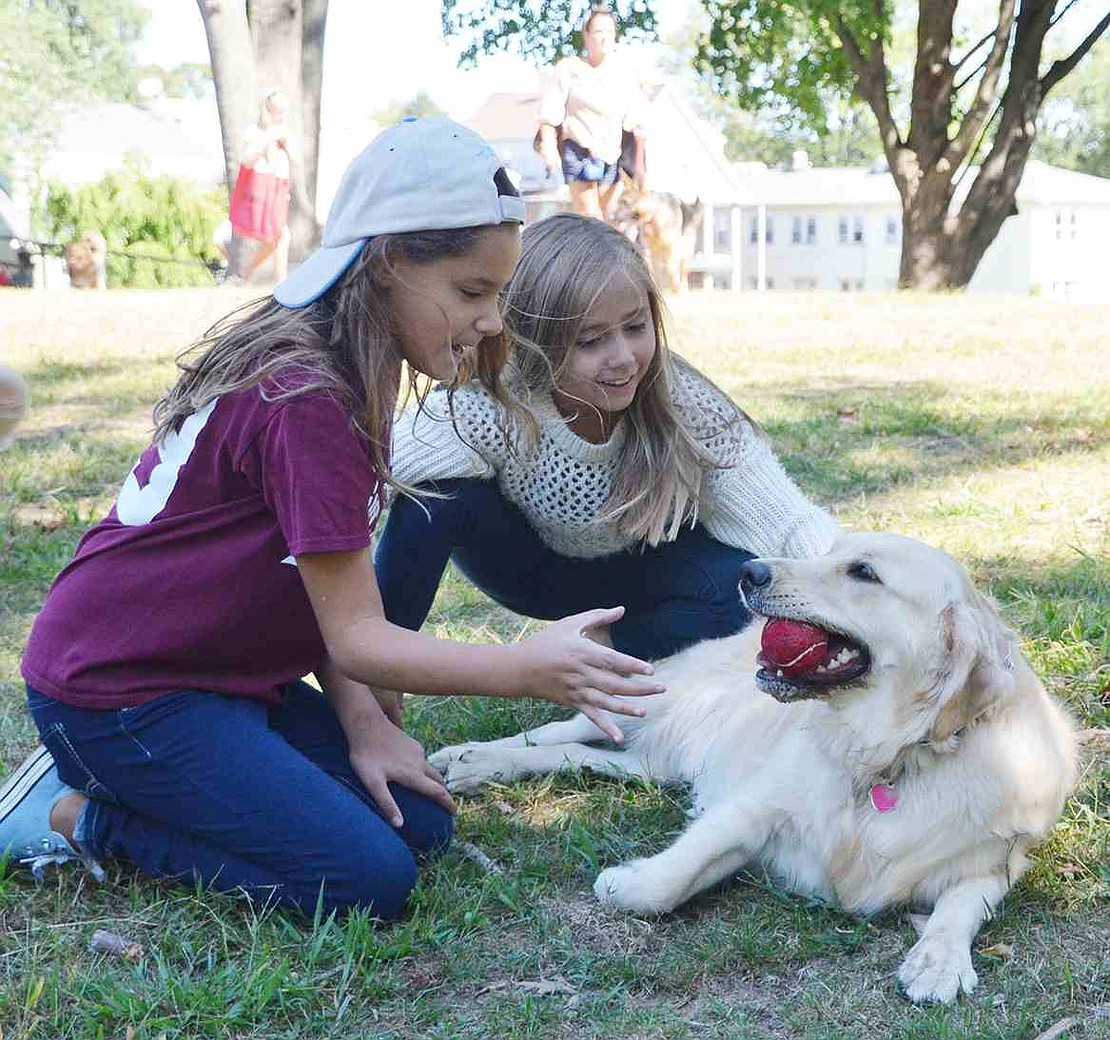 Ten-year-old twins Isabelle and Elia Mateus prepare to retrieve a ball from Gigi to continue their game of fetch. 