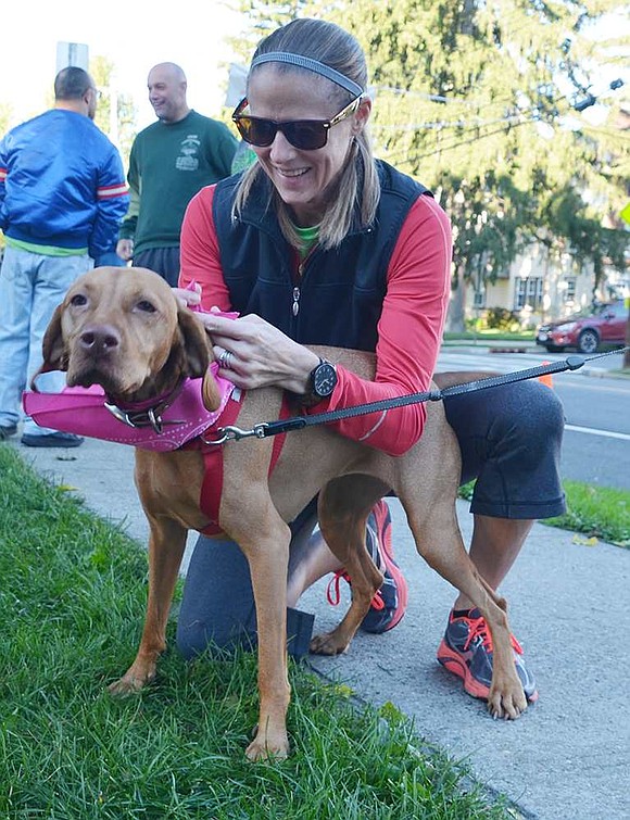 Kristin Budden of Puritan Drive ties a pink bandana around Senna's neck before the walk. All the canines who participated in the new one-mile dog walk earned brightly colored bandanas to wear home.