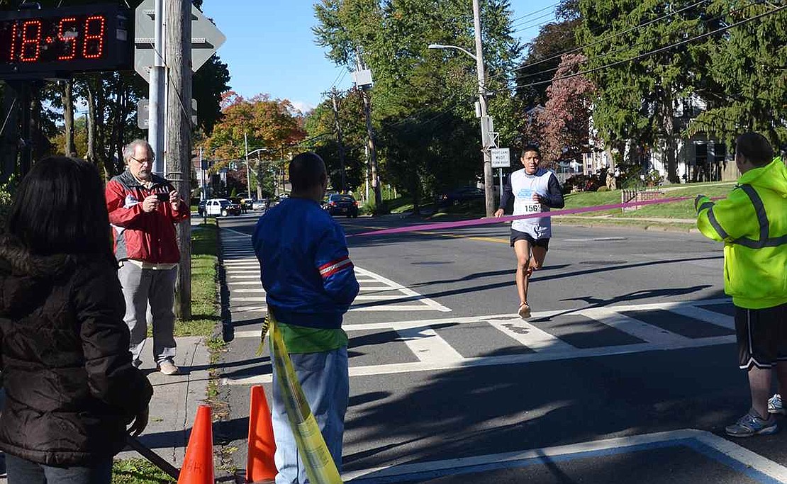 Pedro Yupa of Irving Avenue hustles down Putnam Avenue to cross the finish line. For the second year in a row, the 31-year-old was the first to complete the 5K. This year he did so in 18 minutes, 59 seconds, shaving off 43 seconds compared to last year's race. 