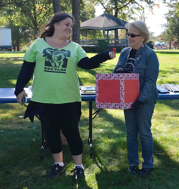 Dina Goren picks a raffle ticket out of the box held by Diane Wright. Five-year-old Martin Yupa won a shared fence dedication at the newly-opened Port Chester Dog Park. 