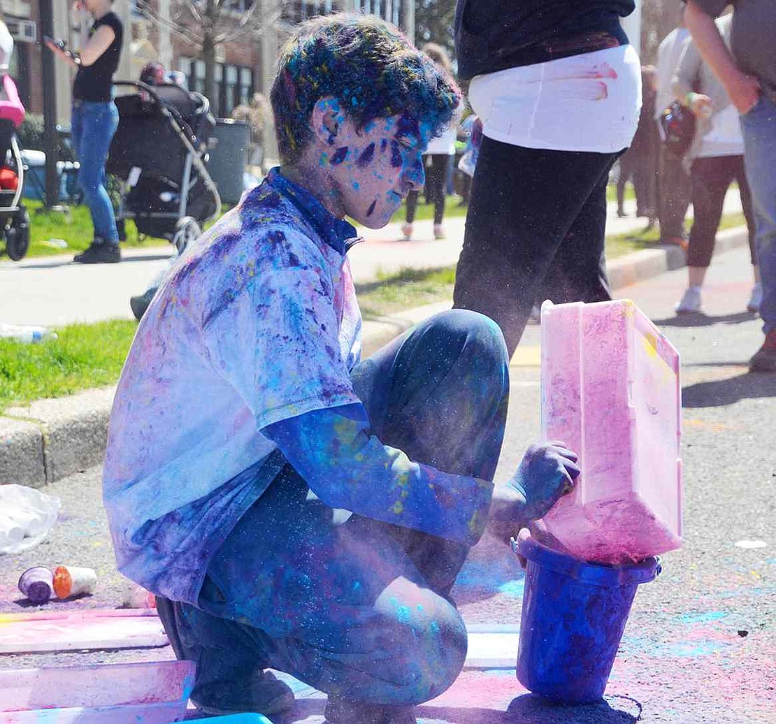 <p class="Picture">Himself covered in blue and purple, an older student refills his bucket with more powder, getting ready for another round of throwing it at the running students.&nbsp;</p>