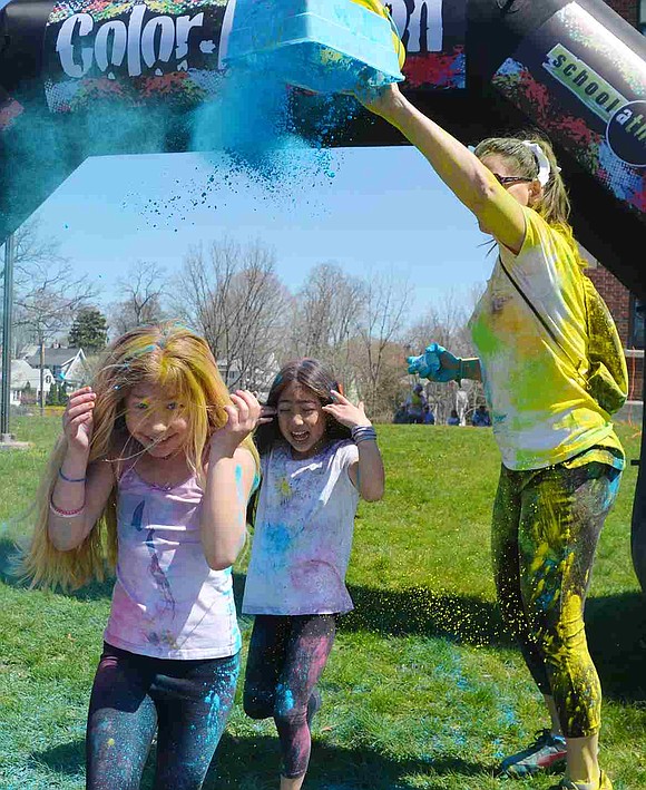 <p class="Picture">Two girls smile even as a volunteer dumps more powder on them.&nbsp;</p>