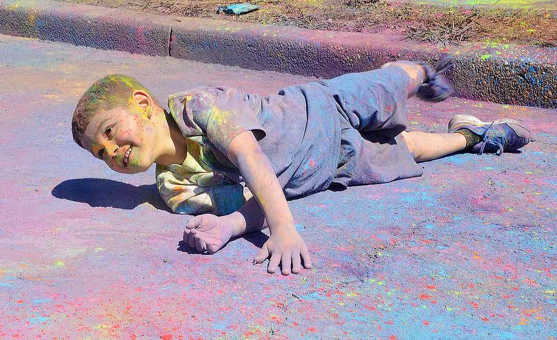 <p class="Picture">Deciding he does not have enough dust on him, Park Avenue School first-grader Roy Morris rolls around on the ground in a pile of the colorful detritus left behind after the run is completed.&nbsp;</p>