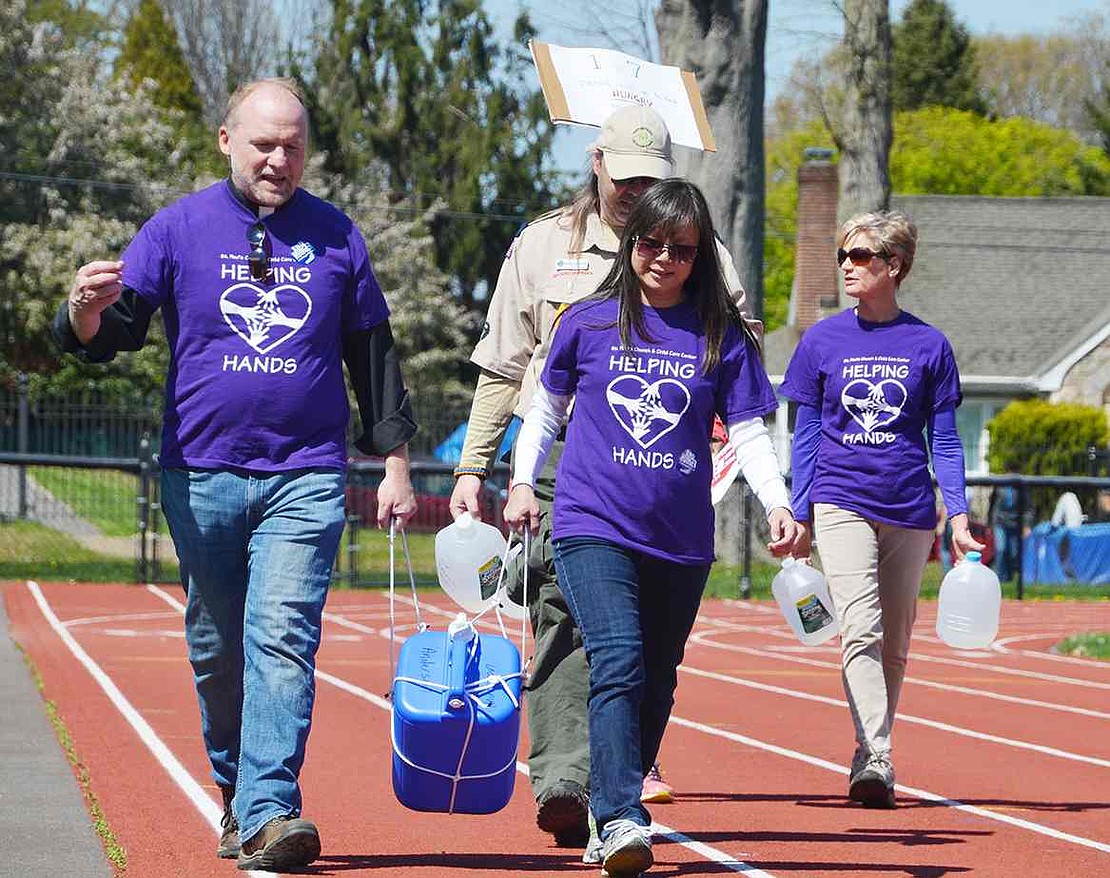 <p class="Picture">Wearing appropriately named Helping Hands t-shirts, Rev. Jim O&rsquo;Hanlon of St. Paul&rsquo;s Lutheran Church in Rye Brook and Laura Chen-Schultz of Port Chester team up to carry a four-gallon container of water.</p> <p class="Picture">An annual fundraiser, the Crop Hunger Walk, raised about $8,600 this year for Church World Service, an international relief and service agency, Neighbor to Neighbor in Greenwich, Conn. and Carver Center in Port Chester. Unlike in past years, the more than 100 participants from Port Chester, Rye Brook and Greenwich carried water around the track at Port Chester High School on Sunday, Apr. 24 to symbolically support the millions in the world, mostly young girls and women, who must carry water for their family&rsquo;s daily needs.</p> &nbsp;