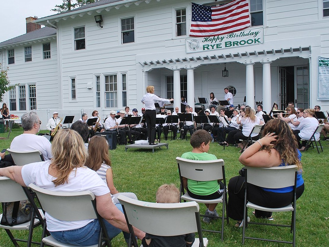 <p class="Picture">Spectators watch and listen to the Rye Town Community Band play their annual concert at the start of the Rye Brook Birthday Party.</p>