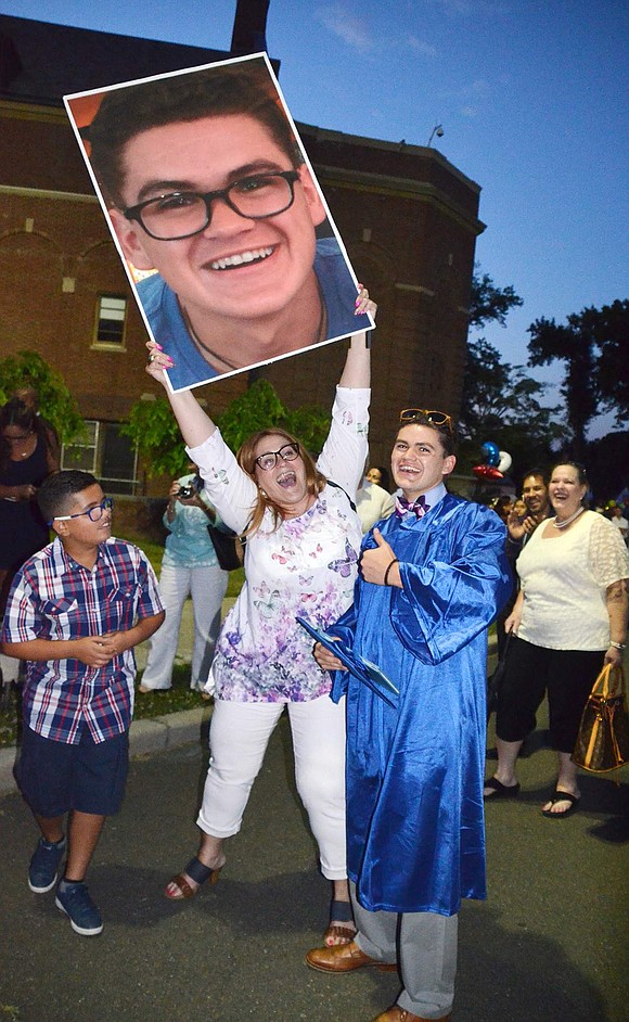 Josie Prieto holds up a huge photo of her son, Carlos Munoz, who stands next to her in the flag plaza following the Port Chester High School commencement on Friday, June 24. &ldquo;After nine months and 18 years, I have every right,&rdquo; she said. Richard Abel|Westmore News<br />