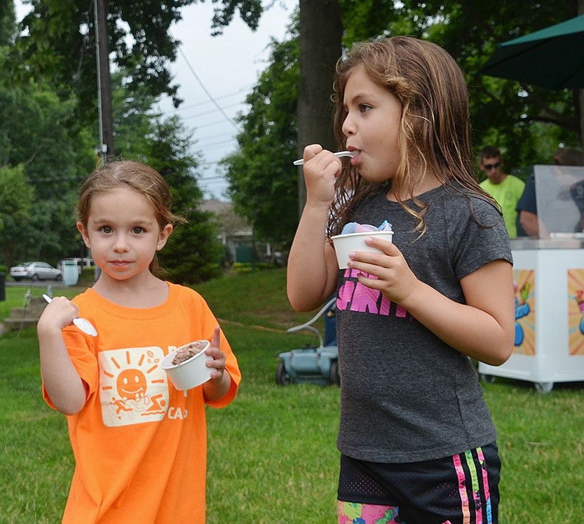 <p class="Picture">Rye Brook siblings Emmie, 5, and Carly, Hodes 7, look to the playground and bounce house as they eat their cups of ice cream.</p>