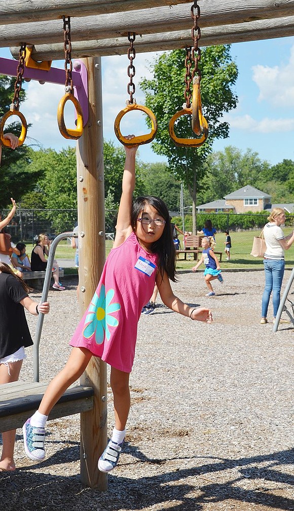 <p class="Picture">Five-year-old Kayla Kim of High Point Circle tests her courage as she swings across the monkey bars. Although she couldn&rsquo;t make it all the way, she will have the whole school year to practice.&nbsp;</p>