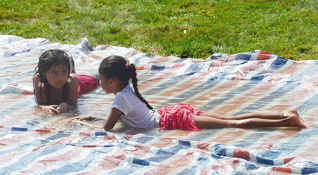 <p class="Picture">Kimberly Pena, 8, of Rye (left) and Bailey Bonilla, 5, of Port Chester have a powwow while keeping cool lounging on a flooded tarp at the fall fundraiser while the outside temperatures soared.</p>