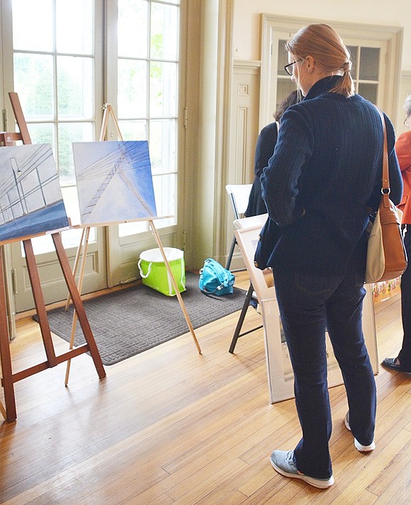 <p class="Picture">Port Chester High School IB Art students had their work displayed during ART10573, even if they were not present for the art show. Reneate Van Der Wateren of South Ridge Street admires a couple of their paintings.&nbsp;</p>