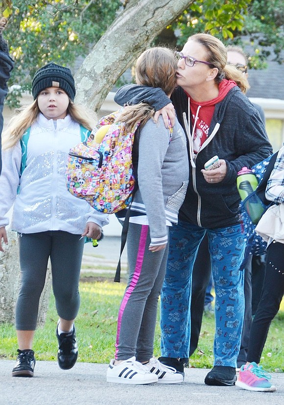 <p class="Picture">Hope Klein gives her fourth grade daughter Madilyn a goodbye hug and kiss while Madilyn&rsquo;s third grade friend Lily Wolf watches.&nbsp;</p>