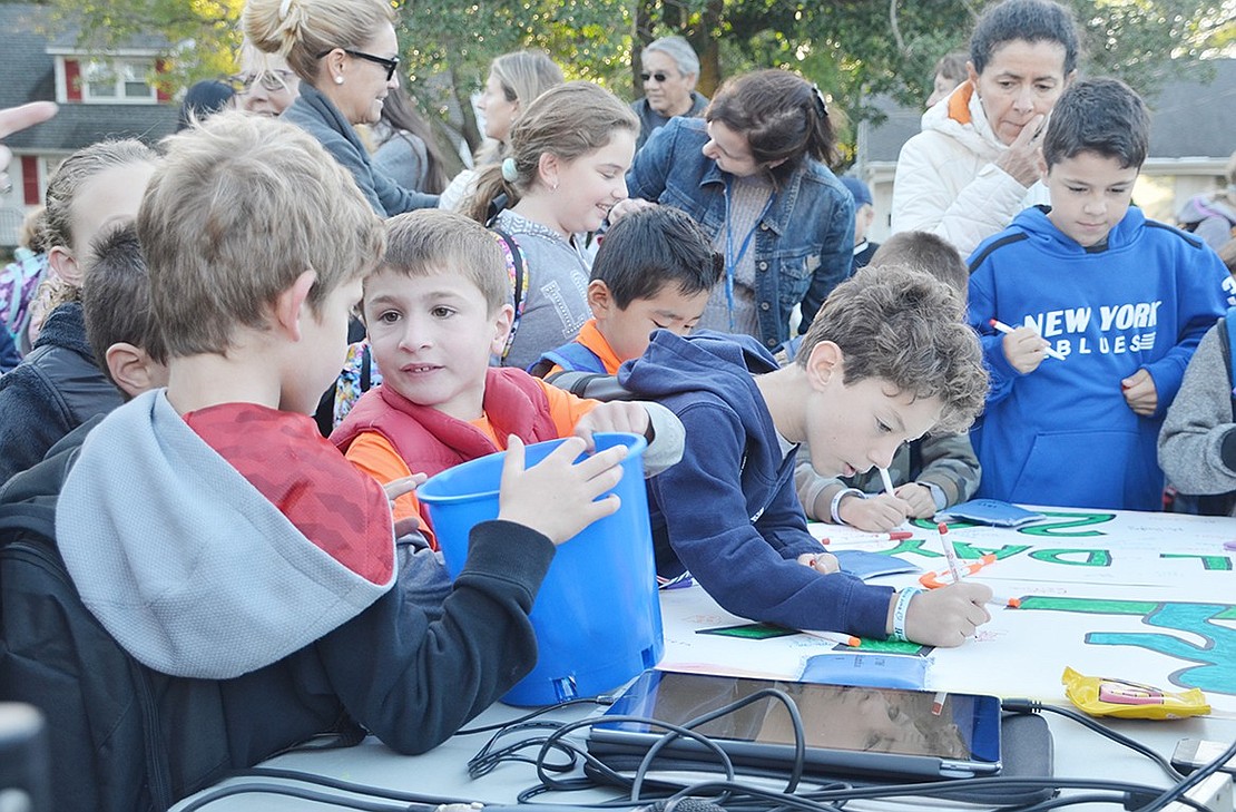 <p class="Picture">As children arrive, they crowd around the sign physical education teacher Ashley Hughes set up on which to write their names. After signing, kids received a bracelet and a flashlight, while they lasted. Hughes led the event and said, &ldquo;I thought it was really great even though the weather was a little chilly. It&rsquo;s great to see all the families and dogs enjoying the morning.&rdquo;</p>