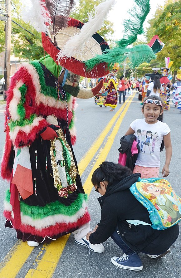 <p class="Picture">A costumed character marching with a Mexican group needs help tying his shoe.</p>