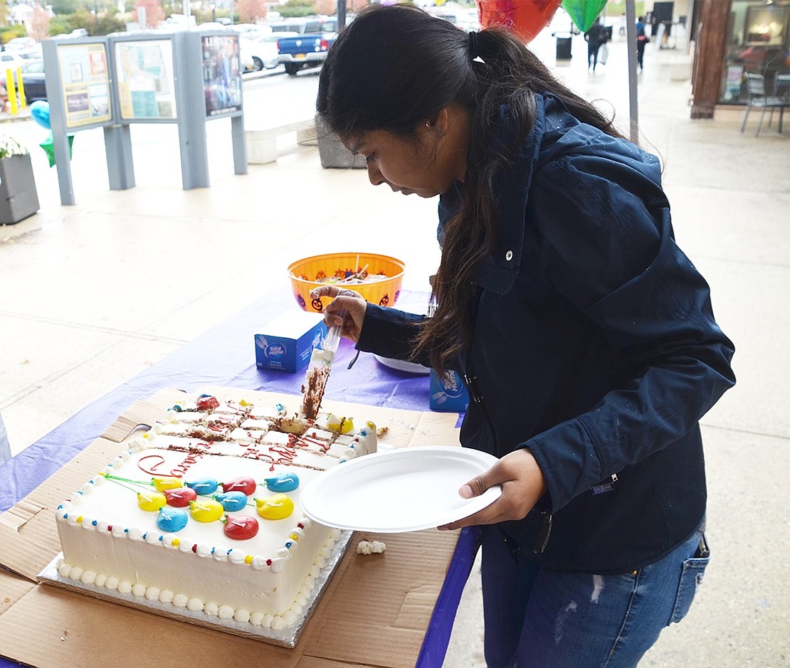 <p class="Picture">Rosa Morocho of South Regent Street cuts Sportech&rsquo;s 25<sup>th</sup> anniversary cake. Even though it was raining, the shop cleared out quickly and a line formed to get a piece of the frosted treat.&nbsp;</p>