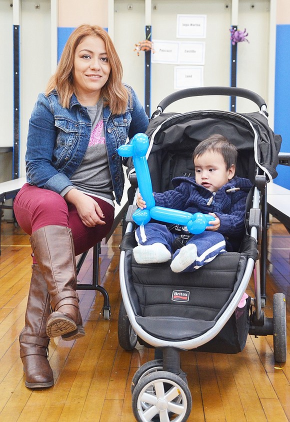 <p class="Picture">Laura Asiain of Clinton Street watches the other kids race around the gym floor as her one-year-old son Sebastian enjoys playing with his blue balloon giraffe.&nbsp;</p>