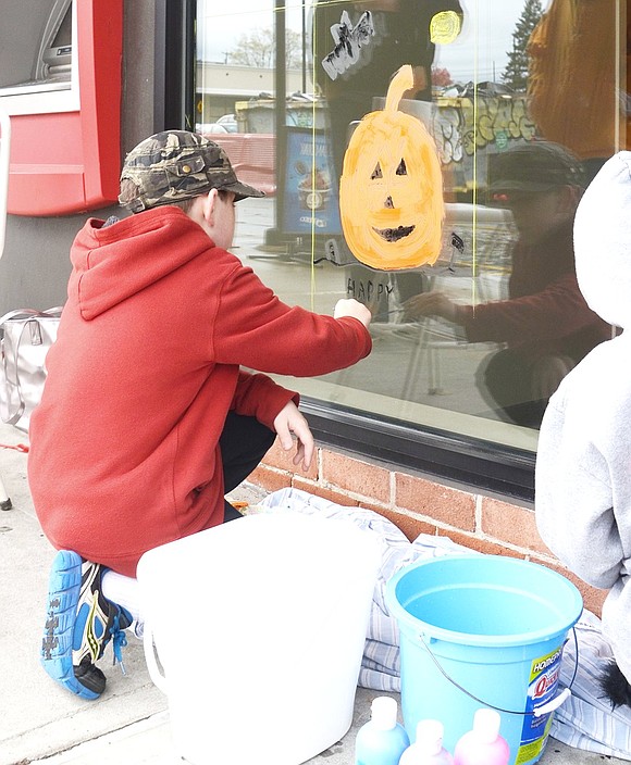 <p class="Picture">Ten-year-old Jackson Welde of Jennifer Lane paints a spooky pumpkin-shaped house on Customers Bank&rsquo;s window.</p>