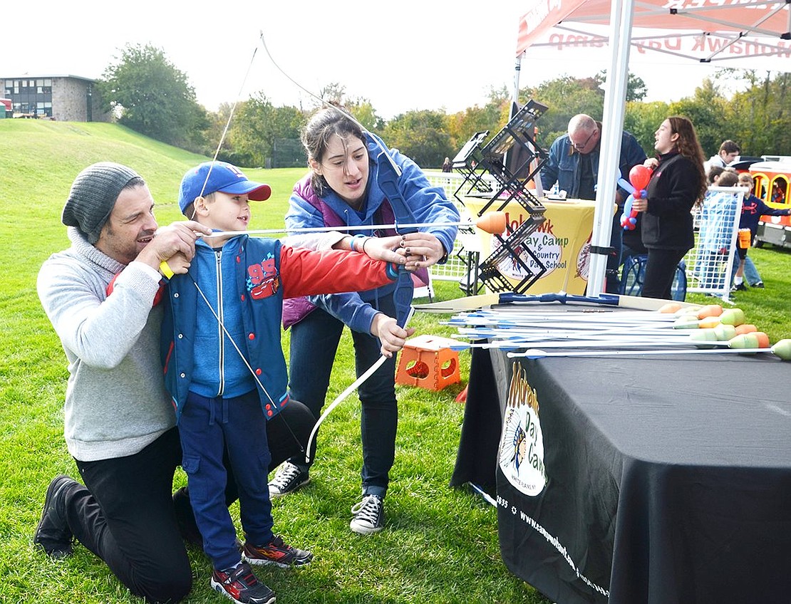 <p class="Picture">After notching his arrow, 5-year-old Lucas DeBar and his father Dan take aim at five floating balls at Mohawk Day Camp&rsquo;s table. The Elm Hill Drive residents worked together to pull back the bow for Lucas&rsquo;s first shot at archery.&nbsp;</p>