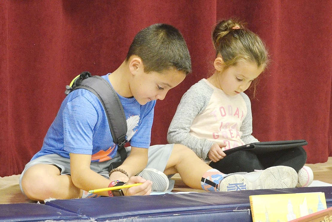 <p class="Picture">Third grader Matty Zimmerman and his 4-year-old sister Mia commandeer the stage as a nice place to sit and play while their mother Luci helps sell books.&nbsp;</p>