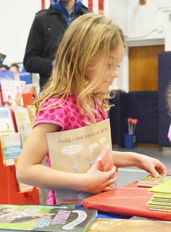 <p class="Picture">Kindergartner Etta Paulson looks over every book she can before choosing another one.&nbsp;</p>