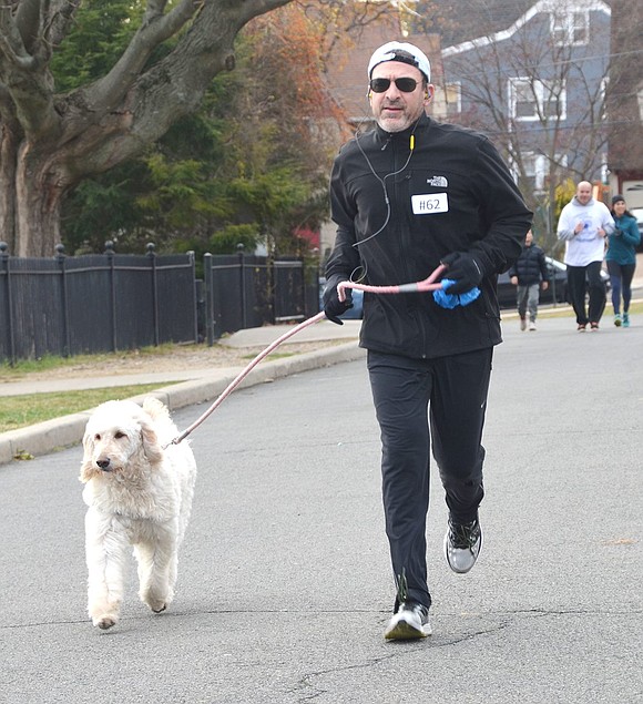 <p class="Picture">David Harman of Argyle Road trots along the course with his golden doodle Scout.</p>