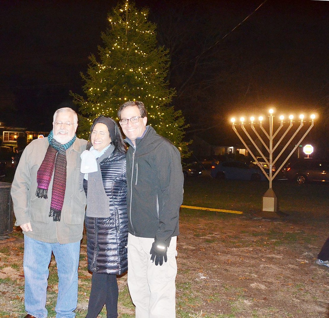 <p class="Picture">Rye Brook Mayor Paul Rosenberg stands with Trustees David Heiser and Susan Epstein in front of the newly lit Christmas tree and menorah.&nbsp;</p>
