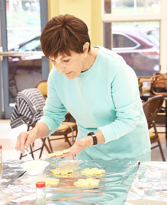 <p class="Picture">Dottie Adolfson of Arrowwood Circle puts a light coat of frosting over the snowflake cookies before putting a dusting of gold sprinkles on top.&nbsp;</p>