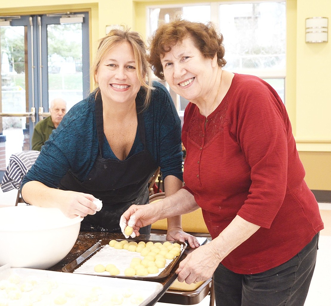 <p class="Picture">Elizabeth Rotfeld poses with a Rye Brook Senior who wished to remain unnamed as they dip snowball cookies into powdered sugar.&nbsp;</p>