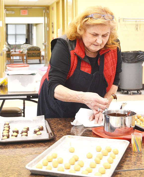 <p class="Picture">PeggeAnn Larywon of Rye Brook dips buckeyes into melted chocolate.&nbsp;</p>