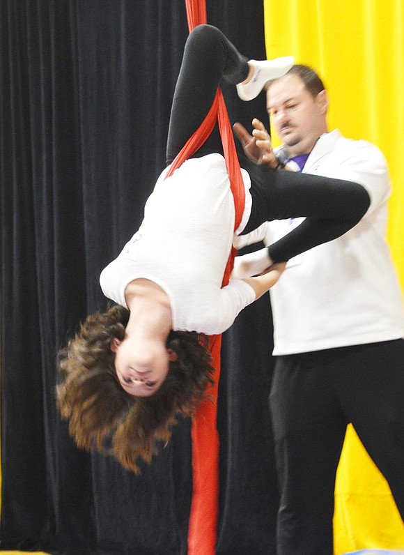 <p class="Picture">Grace Brunetti lives up to her name as she elegantly sways and spins on a hanging ribbon. Physical Education teacher Steve Forzaglia offers his assistance to help keep her spinning and balanced.</p>