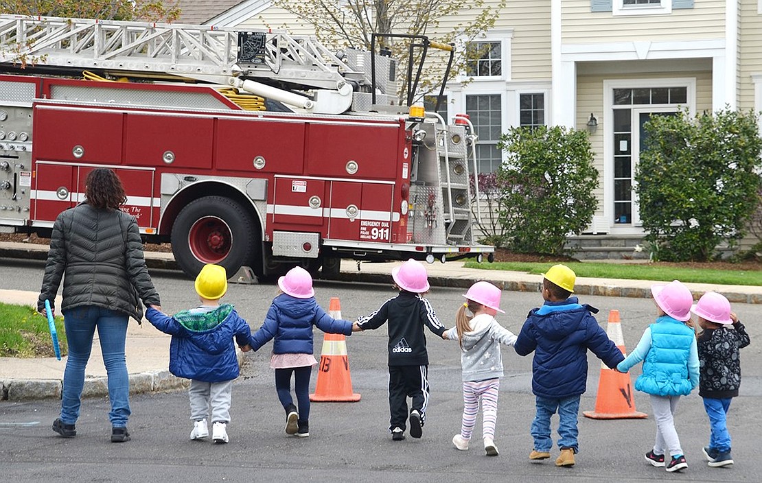 Teacher leads a class of 3-year-olds over to their next station—the fire truck.