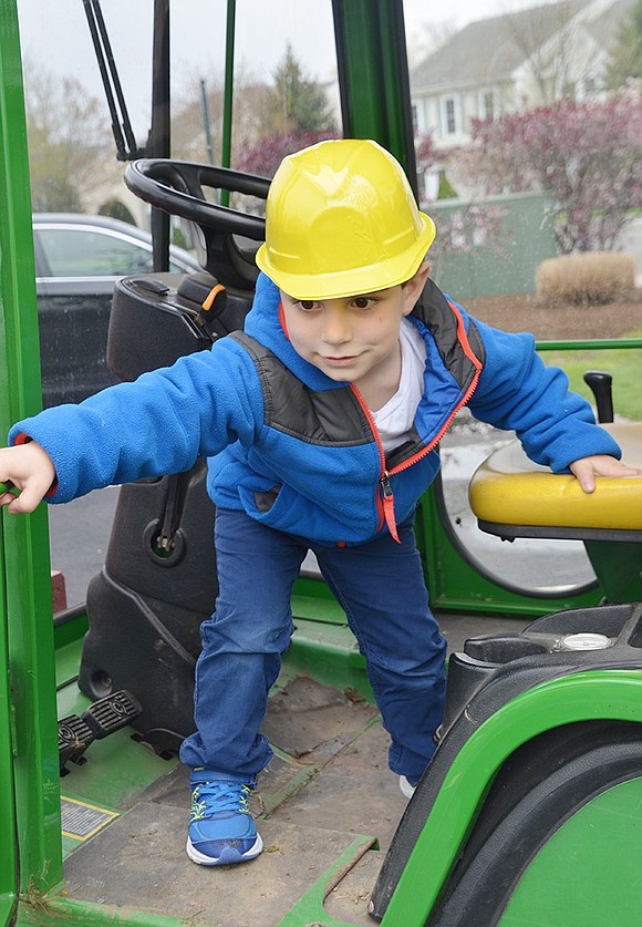 Three-year-old Eddie Rizzo means business. He closes the door of the village’s green John Deere lawnmower/tractor before mounting the seat and pretending to drive away.