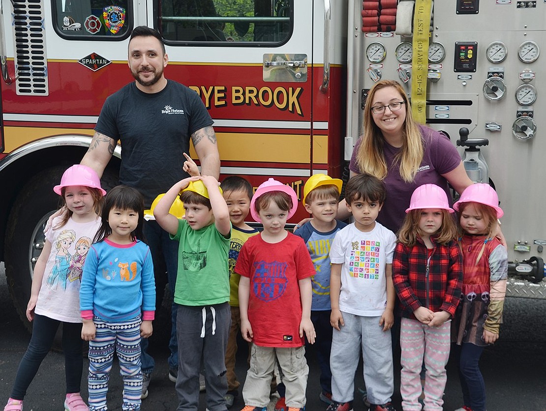 Teachers Nick Pagan and Cassandra Novello stand with 4-year-olds, from left, Elena McGlynn, Jaime Chen, unidentified upon request, Miles Yan, Ben Zimmerman, Nicholas Gerosa, Nicolas Afshar, Morgan Schwartzstein and Molly Williams in front of a Rye Brook fire truck.