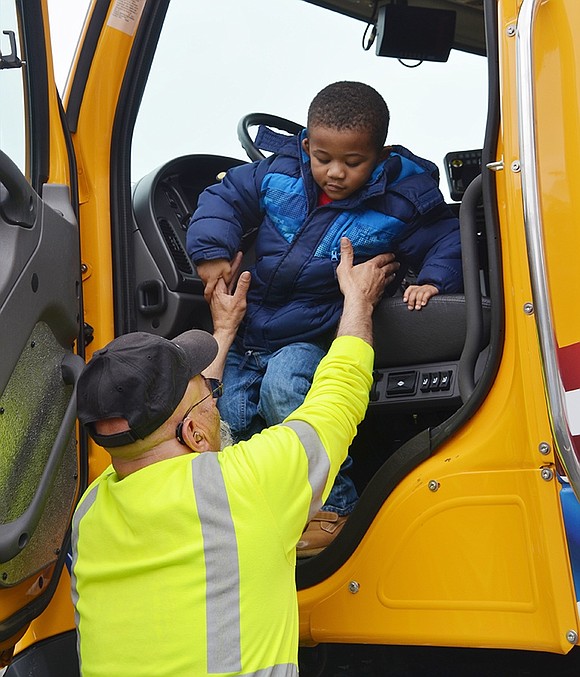 Mechanical Equipment Operator Ralph D’Ottavio catches 3-year-old Matthew Pitter as he slides out of one of the village’s plow trucks.