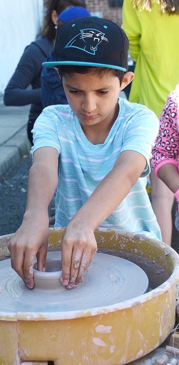 Instilling a passion for creation is what the Clay Art Center is all about, which is why the Beech Street ceramic arts venue had a pottery wheel for kids to try out during their Spring Fest and Super Pottery Sale on Saturday, June 3. Ten-year-old Kenny Orozco of Willett Avenue is all smiles as he tries to make his own pot. 