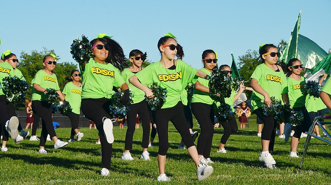 Showing off their green spirit are Thomas A. Edison School students. The girls wave pompoms and the boys twirl flags. 