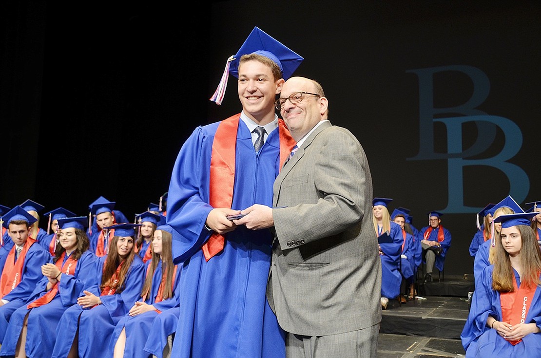 Proud father and former Board of Education President Stephen Kaplan presents his youngest son Spencer with his diploma. 