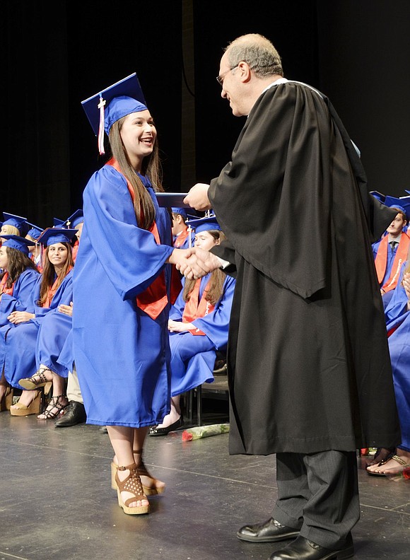 Rachel Sarch is one of the first to walk across the stage and gives Board of Education President Jeff Diamond a huge smile when receiving her diploma. 