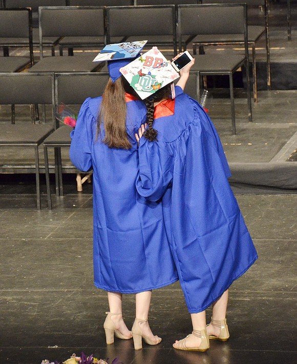 Wait! Let’s take a selfie! Two girls thought the filled auditorium was a perfect background for a graduation photoshoot. 